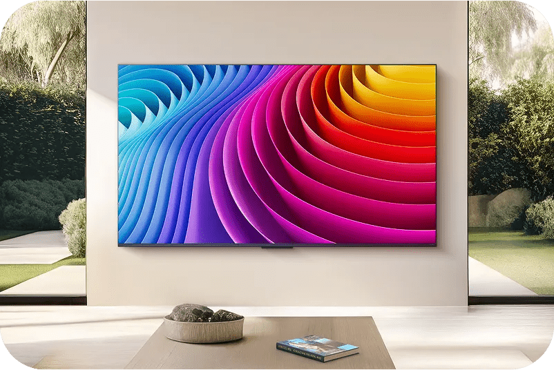 A modern living room has a large QNED TV screen mounted on the wall. The QNED showcases a rainbow design on its screen.